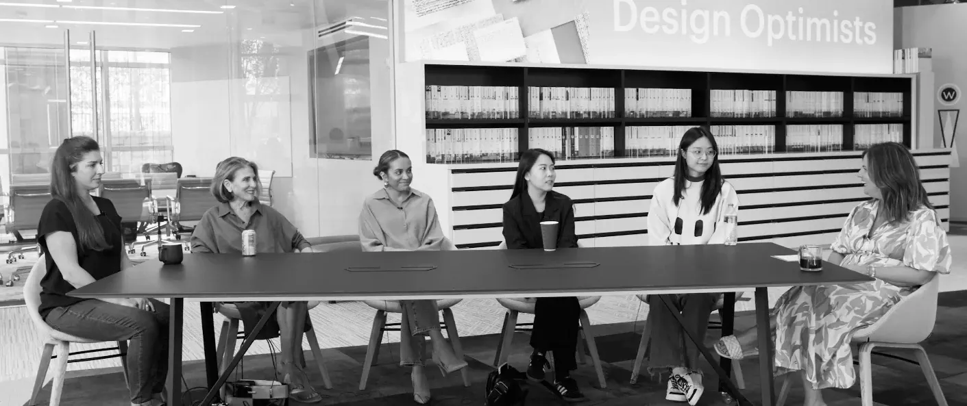 Modern workplace meeting room with a group of people seated around a table, featuring contemporary office furniture and flooring