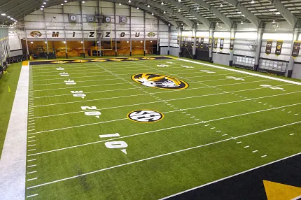Artificial Turf Field in Indoor Sports Facility with Mizzou Branding Indoor sports facility with artificial turf field featuring Mizzou and SEC logos