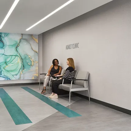 Modern Healthcare Facility Waiting Area with Teal and Gray Flooring Healthcare facility waiting area with modern design featuring teal and gray flooring, abstract wall art, and two women seated on chairs