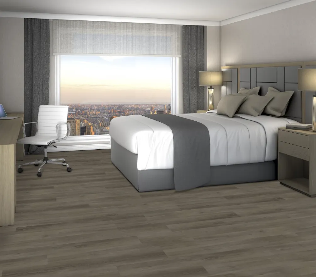 Modern hotel room with a large bed, desk, and chair, featuring wood-look flooring and a city view from the window
