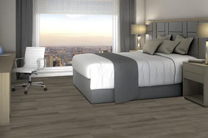 Hospitality room with wood-look flooring and city view Modern hotel room with a large bed, desk, and chair, featuring wood-look flooring and a city view from the window