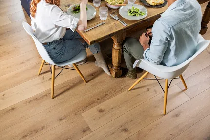 Coretec Residential SPC Luxury Vinyl Plank Flooring - Natural Wood Look, 72.83x9.06 inch Dining room scene with young couple enjoying a meal on Coretec Residential SPC luxury vinyl plank flooring in a natural wood look, 72.83x9.06 inch dimensions