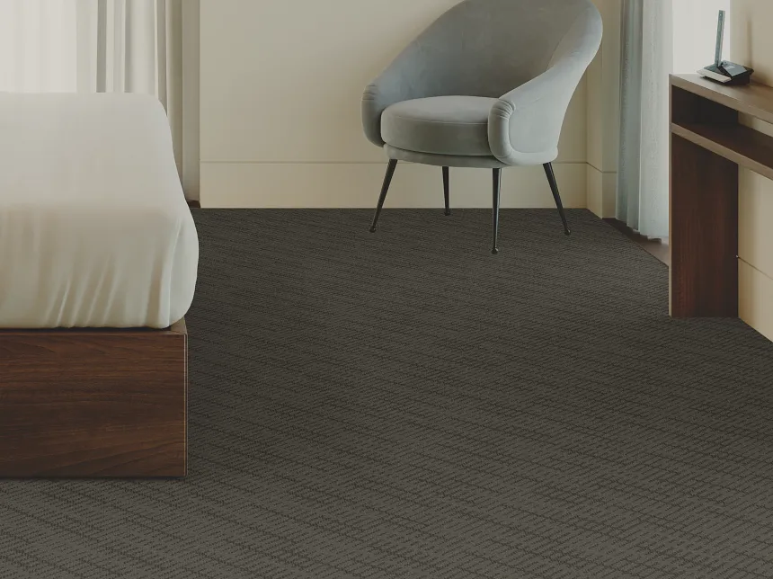 Modern Bedroom with Dark Patterned Commercial Carpet Tile Flooring Modern bedroom with dark patterned commercial carpet tile flooring, featuring a wooden bed frame and a gray armchair