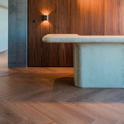 Modern reception desk with designer lighting, rich walnut storage room and rich wood herringbone floors