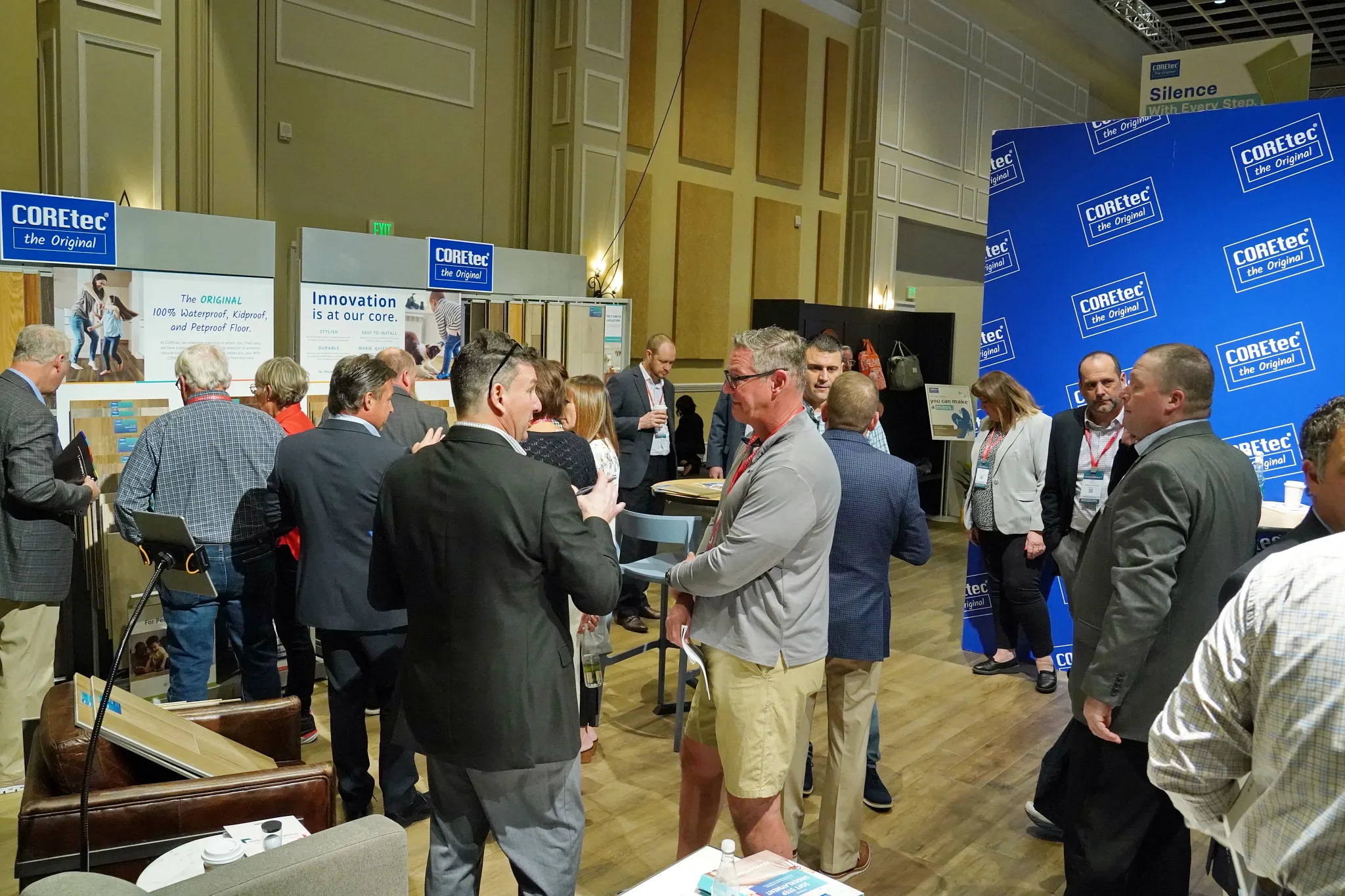 Group of people at a flooring trade show with COREtec branding and luxury vinyl flooring display