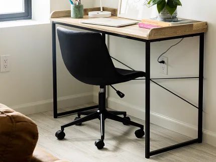 Stylish home office with durable laminate flooring for everyday comfort Modern home office with light wood-look laminate flooring, black office chair, and wooden desk with decor