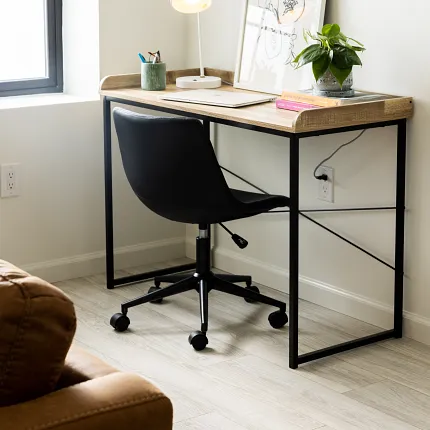 Stylish home office with durable laminate flooring for everyday comfort Modern home office with light wood-look laminate flooring, black office chair, and wooden desk with decor