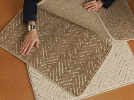 Textured Carpet Swatches in Brown and Gray - Detailed View Close-up of a person holding various carpet swatches with textured patterns in shades of brown and gray