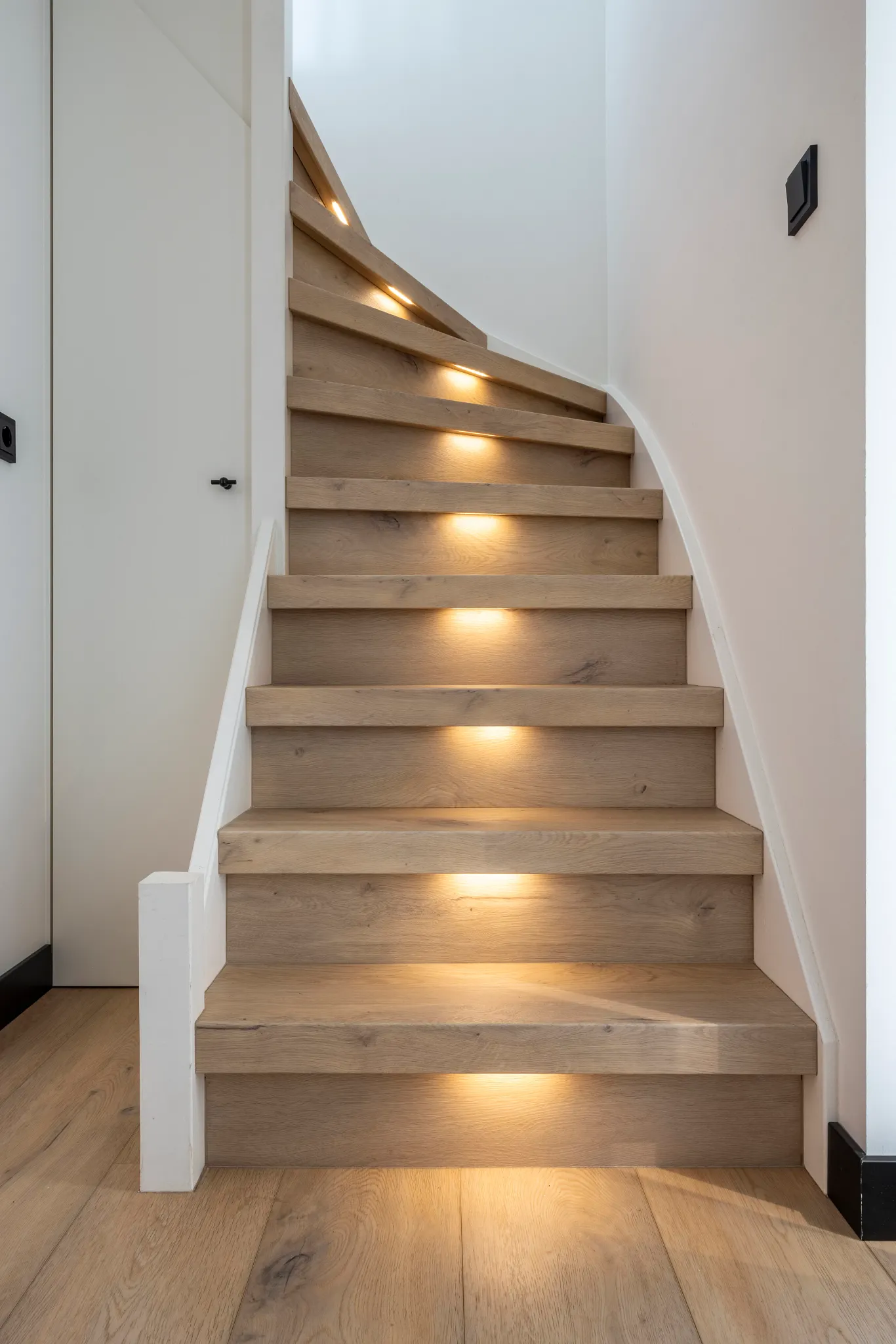 Modern staircase with oak hardwood flooring and integrated lighting