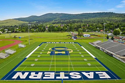 Football field with artificial turf and scenic surroundings. Aerial view of a football field with artificial turf
