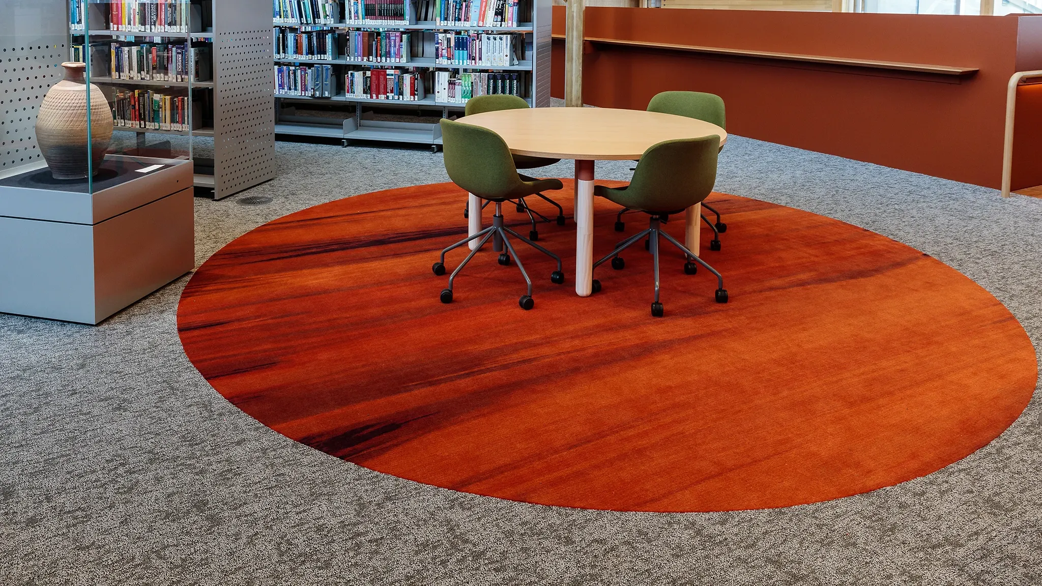 Table with four chairs, next to bookshelves and a vase on display