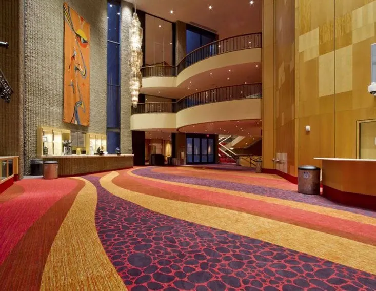 Luxurious hospitality facility lobby with vibrant red, orange, and purple commercial broadloom carpet featuring abstract patterns