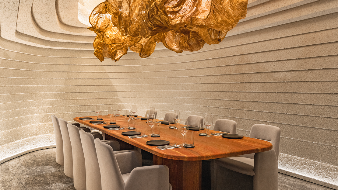 Elegant dining room with a long wooden table, beige upholstered chairs, and a unique textured ceiling design