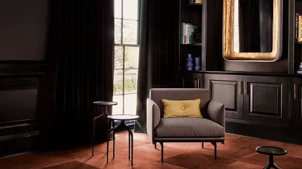 Dye Lab Carpet Tile in Hospitality Lounge Setting | Shaw Contract Hospitality lounge featuring Dye Lab carpet tiles in warm copper and bronze tones with a patchwork installation, lounge seating, dark wall panelling and floor-to-ceiling curtains.