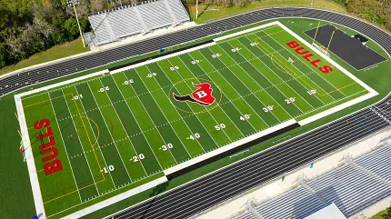 Modern sports field with track and team branding Aerial view of a football field with "BULLS" logo and track