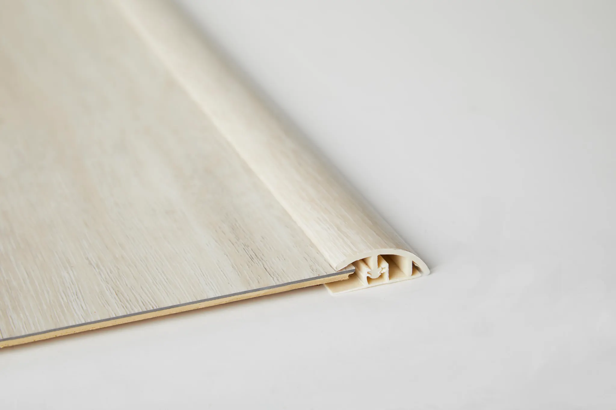 Light wood-colored flooring transition strip on white background