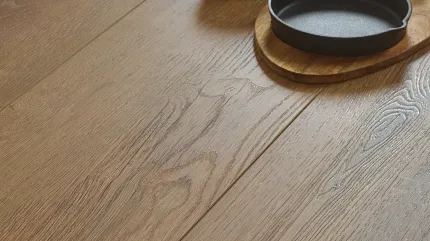 Natural Oak Wood Look Luxury Vinyl Plank Flooring - Durable and Stylish LVP Close-up of wood look luxury vinyl plank flooring with a natural oak finish, featuring a black cup and skillet on a wooden board.