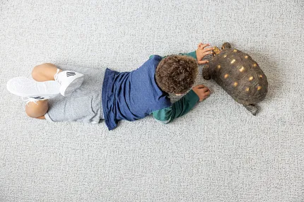 Comfortable and durable flooring for family spaces Child playing on soft surface flooring with a toy turtle
