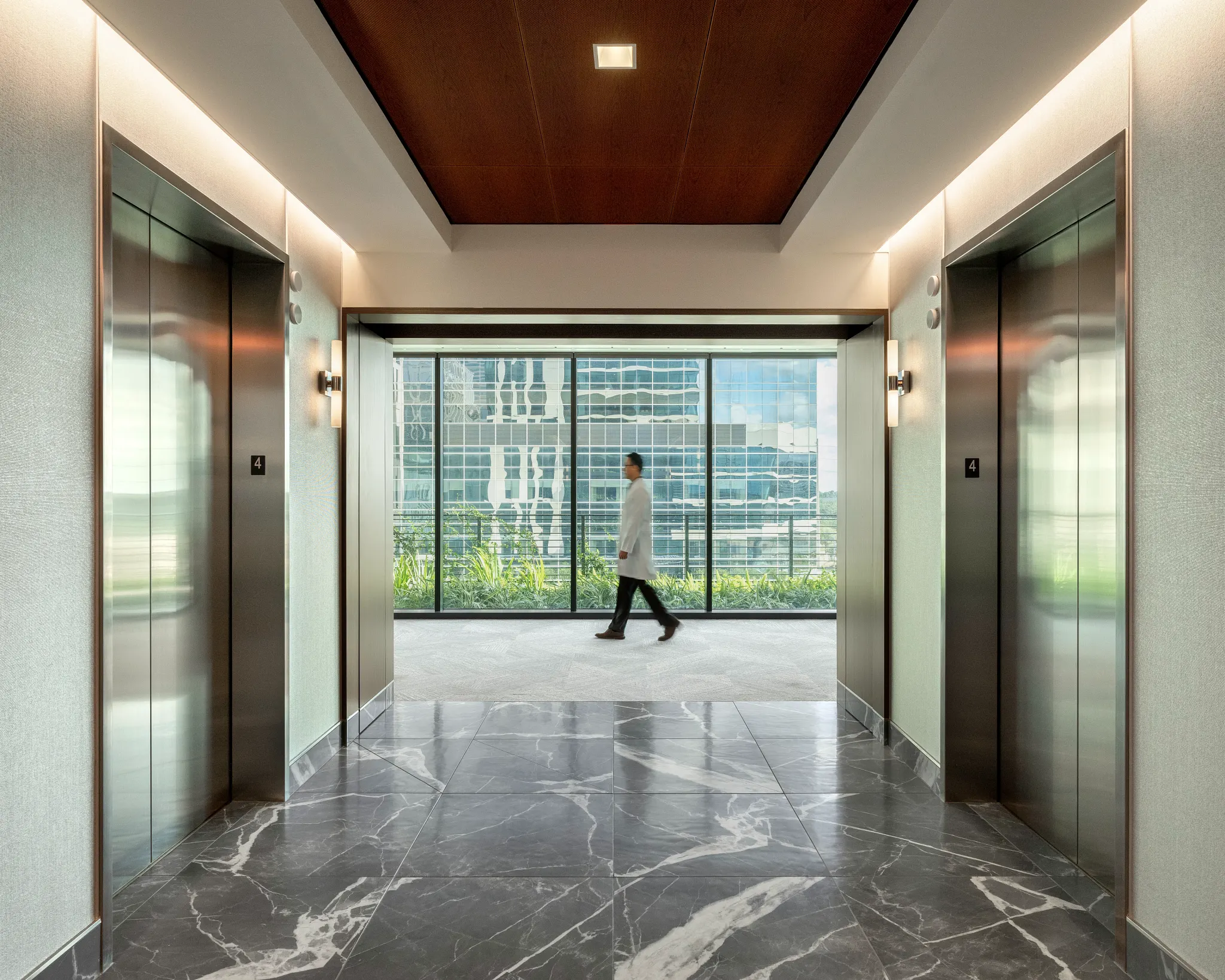 Modern healthcare facility hallway with marble flooring and elevators
