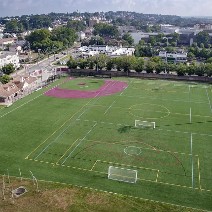 Sports complex with artificial turf fields and running track aerial view Aerial view of a sports complex featuring artificial turf fields with soccer goals and a running track