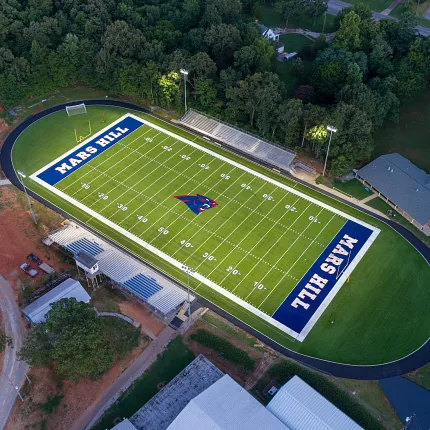 Artificial Turf Football Field Aerial View Aerial view of a football field with artificial turf surrounded by trees and buildings