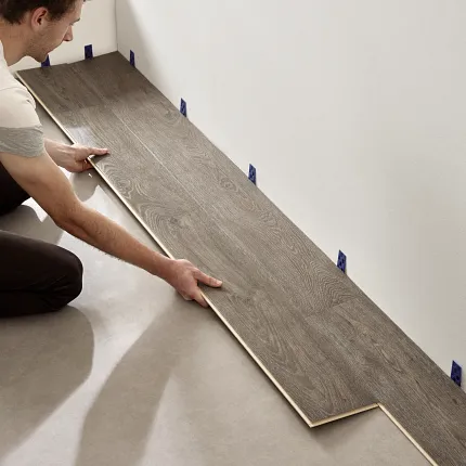 Easy to install wood look luxury vinyl plank flooring installation Man installing wood look luxury vinyl plank flooring in a room