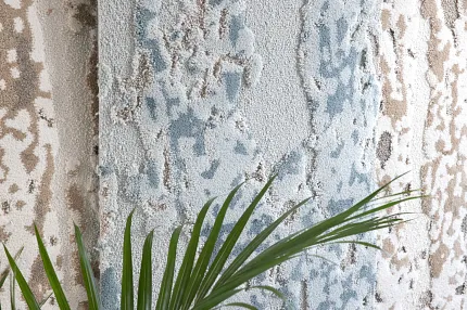Blue and Beige Textured Carpet Swatch with Plant Textured carpet swatch in blue, beige, and cream colors with a leafy plant in the foreground
