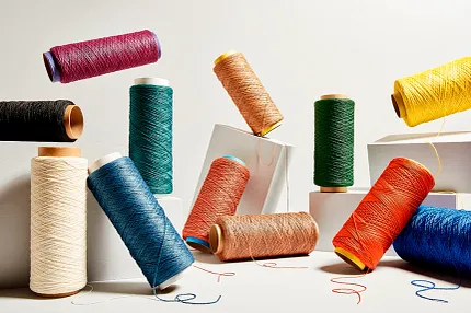 Colorful Yarn Spools for Flooring Design Inspiration Spools of colorful yarn in various shades including red, blue, green, yellow, orange, and black arranged on a white background