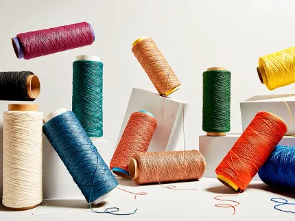 Colorful Yarn Spools for Flooring Design Inspiration Spools of colorful yarn in various shades including red, blue, green, yellow, orange, and black arranged on a white background
