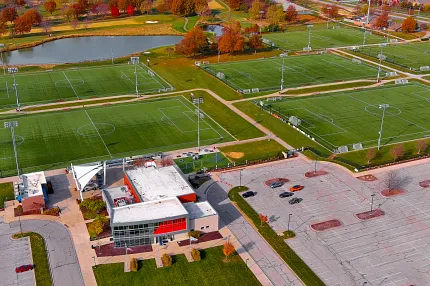 Sports complex with artificial turf soccer fields and autumn scenery Aerial view of sports complex with multiple artificial turf soccer fields and surrounding autumn landscape