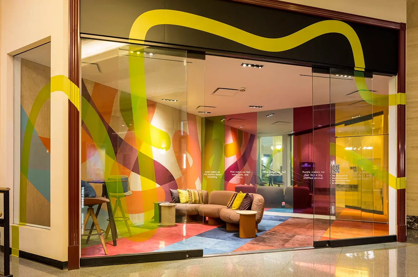 room with glass windows, a brown couch, blue carpet tile, orange carpet tile, and pink carpet tile