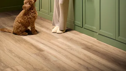 Cozy Kitchen with Green Cabinets and Luxury Vinyl Flooring: Modern Home Design Woman in cozy kitchen with green cabinets and luxury vinyl flooring, holding a cup while a dog looks up at her