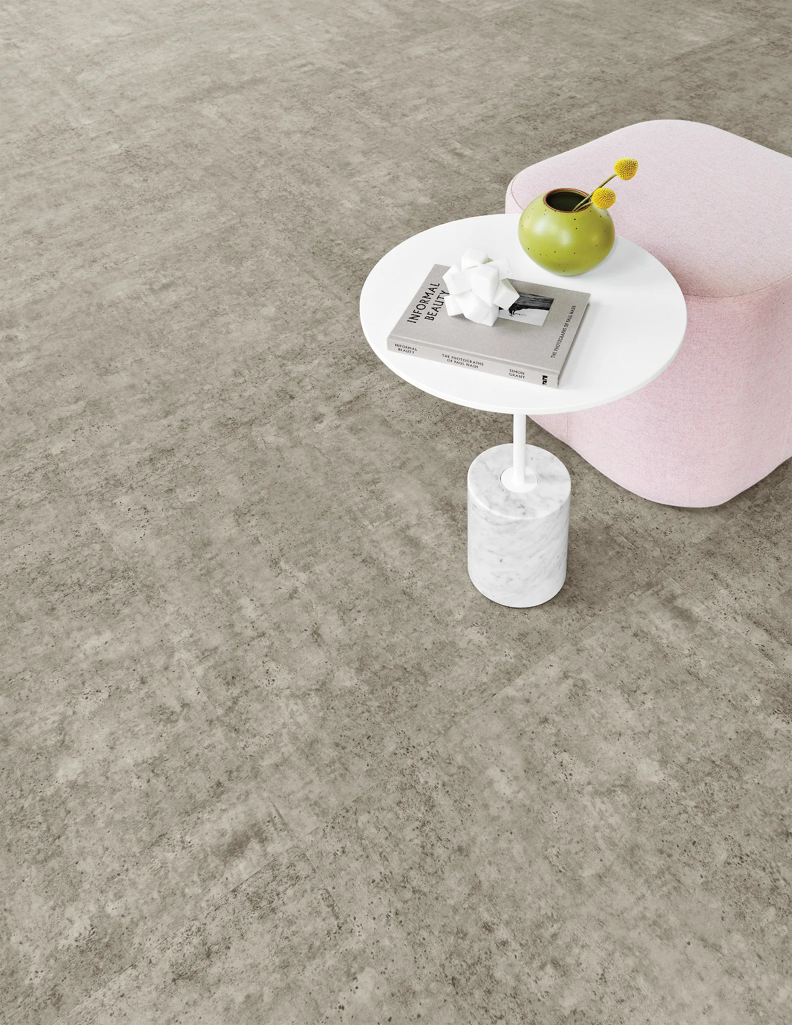 Modern room scene with heavy commercial luxury vinyl tile flooring in a neutral tone, featuring a pink chair and a white marble side table with a green vase and book, 24x24 inch LVT flooring in a contemporary setting