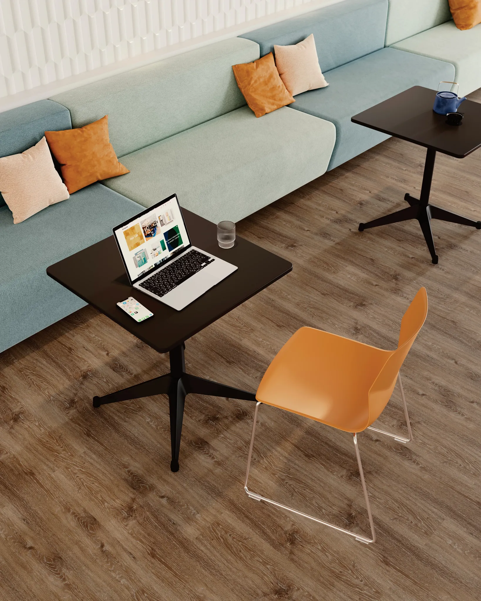 Modern workspace with light brown wood-look flooring, black tables, orange chair, and pastel blue sofa with pillows