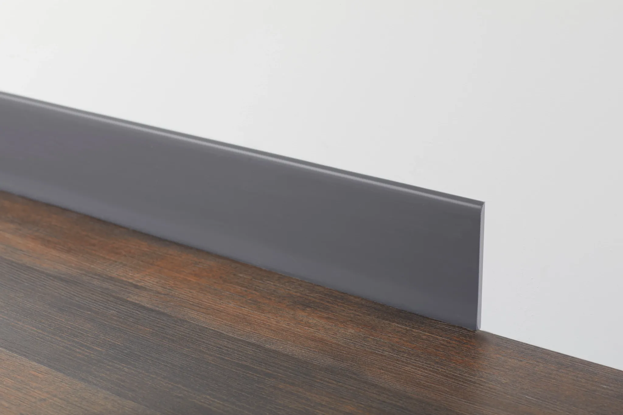 Dark wood flooring with gray baseboard against a white wall