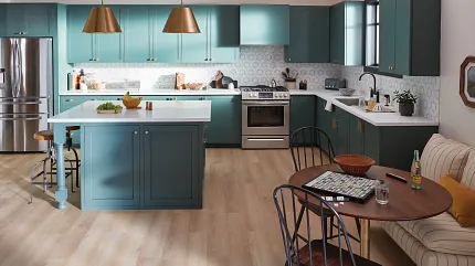 Contemporary kitchen design with durable light wood flooring and teal cabinetry Modern kitchen with teal cabinets, brass pendant lights, and light wood flooring