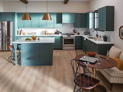 Contemporary kitchen design with durable light wood flooring and teal cabinetry Modern kitchen with teal cabinets, brass pendant lights, and light wood flooring