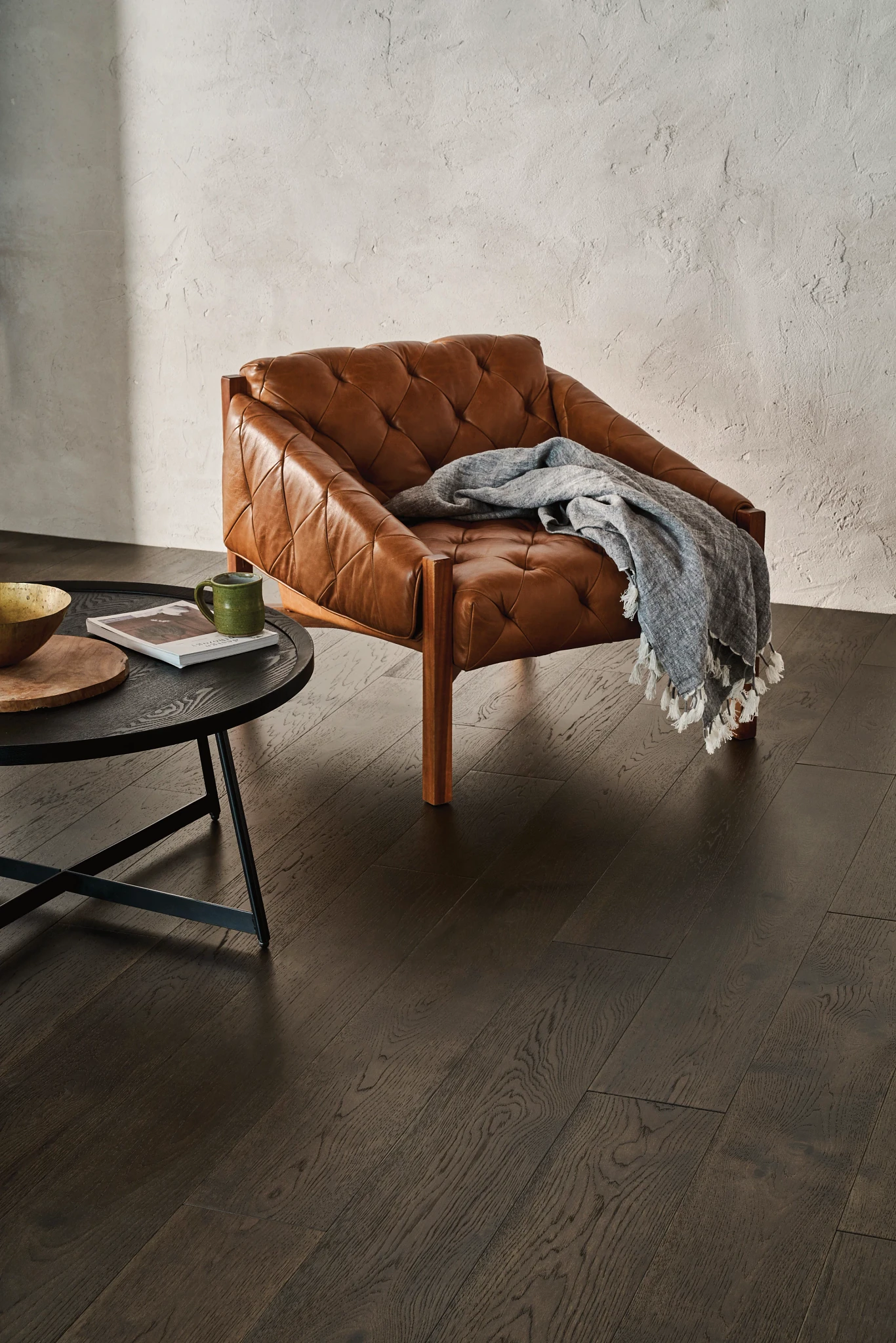 Elegant dark hardwood flooring in a modern living room with a leather armchair and round coffee table
