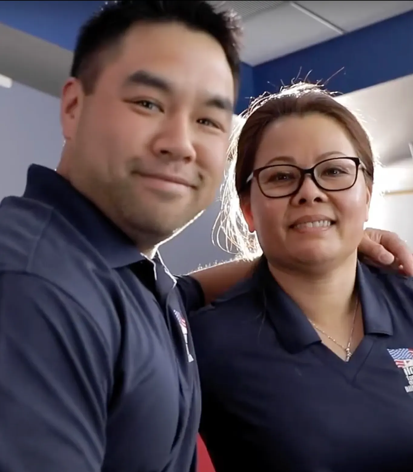 Two people in a professional setting wearing navy blue uniforms
