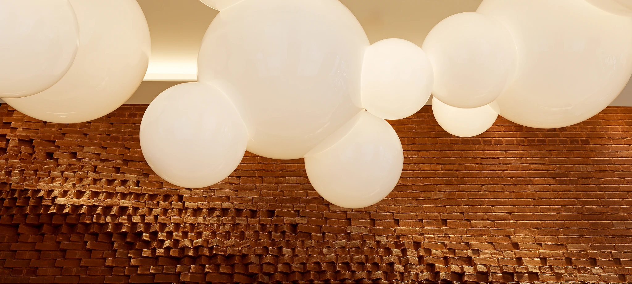 Modern interior design with large white spherical ceiling lights and textured brick wall