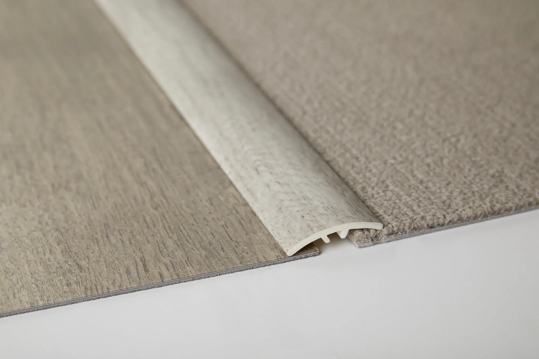 Flooring transition strip between light wood and beige carpet