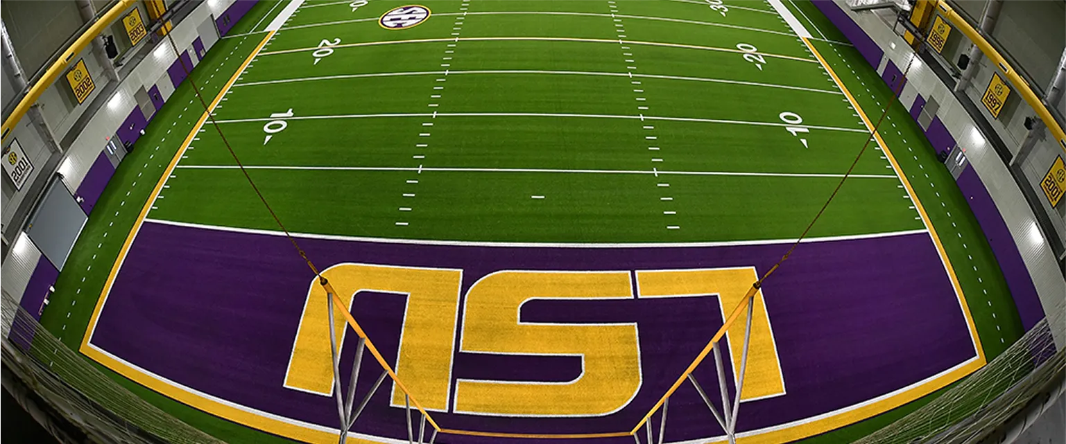 Artificial turf football field with LSU logo in purple and gold colors