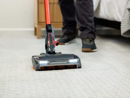 A person vacuuming low pile white patterned carpet A person vacuuming low pile white patterned carpet
