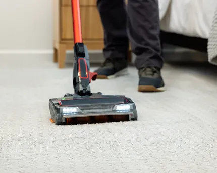 Easy-to-maintain carpet for everyday comfort Vacuuming soft surface carpet in a cozy bedroom