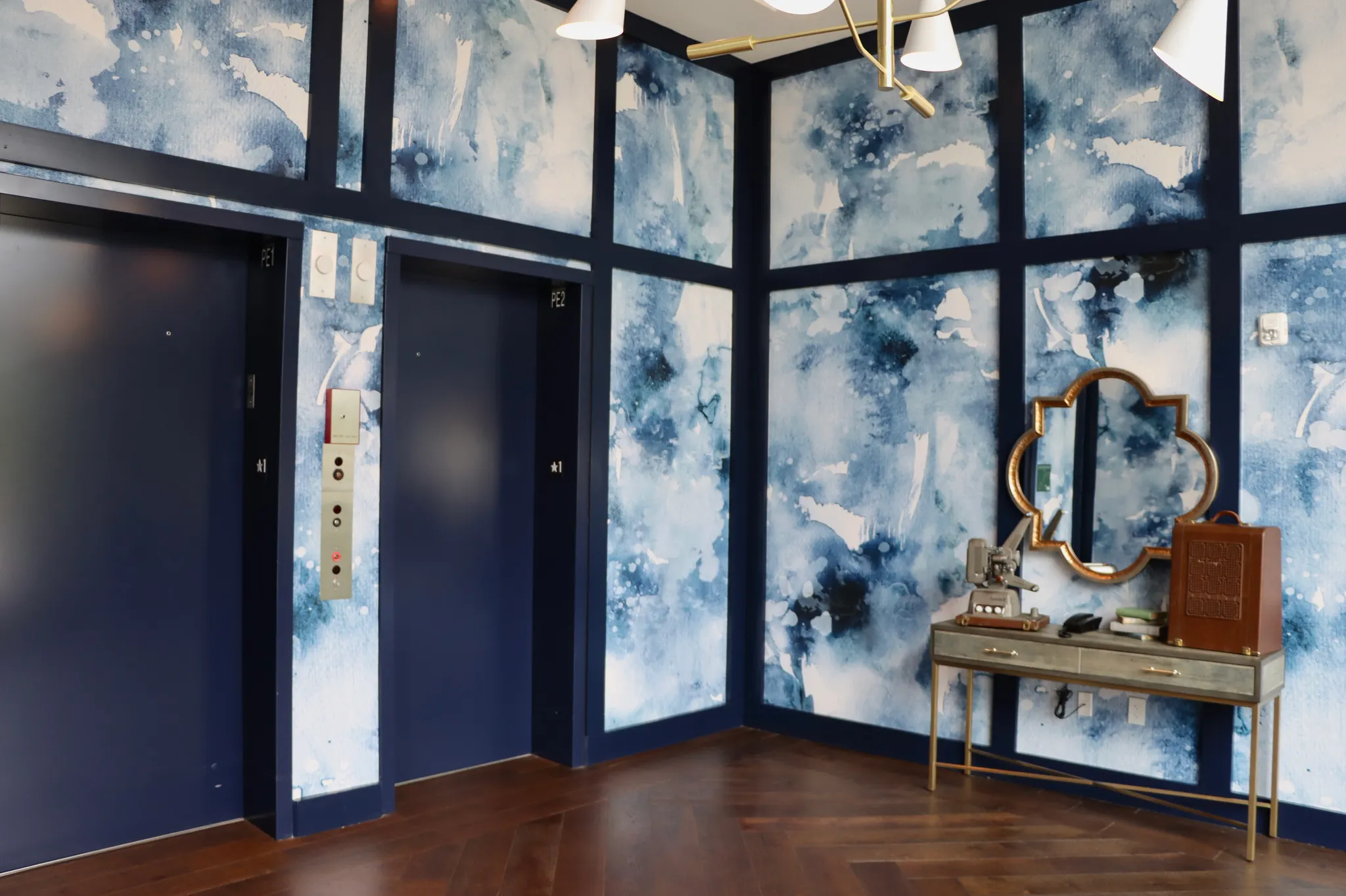 Modern elevator lobby with blue abstract walls and dark wood flooring