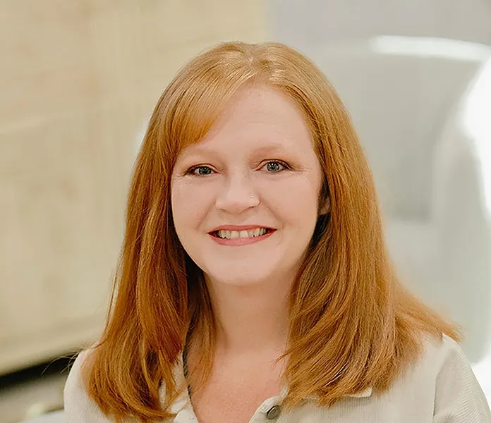 A business style headshot of a woman with red hair and a white shirt