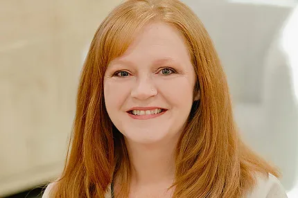 A business style headshot of a woman with red hair and a white shirt