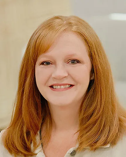 A business style headshot of a woman with red hair and a white shirt