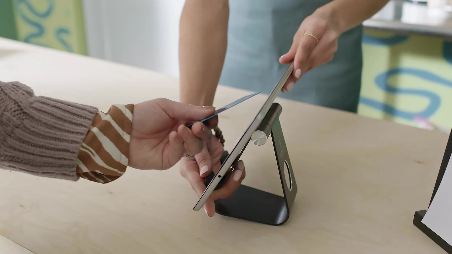 Two people making a contactless payment using a tablet on a stand