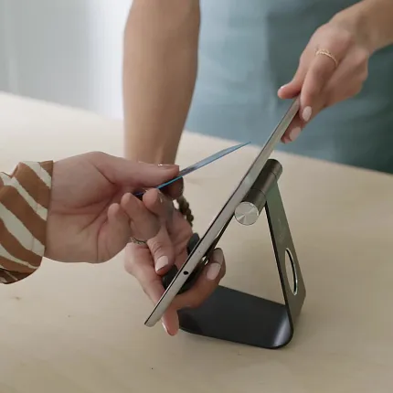 Contactless Payment with Tablet Technology Two people making a contactless payment using a tablet on a stand
